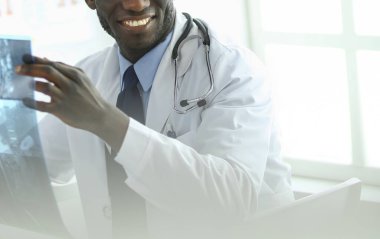 Genç Afrikalı doktor portresi hastaların röntgenlerini tutuyor.