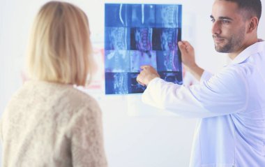 Yakışıklı doktor genç bayan hastasıyla konuşuyor ve ofisinde otururken notlar alıyor..