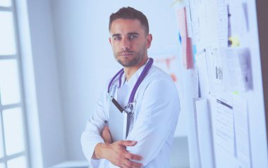 Genç ve kendinden emin erkek doktor portresi tıp ofisinde duruyor..