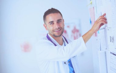 Genç ve kendinden emin erkek doktor portresi tıp ofisinde duruyor..