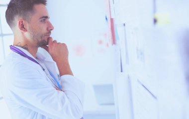 Genç ve kendinden emin erkek doktor portresi tıp ofisinde duruyor..