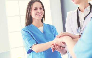 Doktorlar ve hemşireler tıbbi bir ekipte el ele tutuşuyorlar.