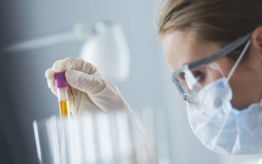Laboratuvarda sıvı yeşil çözeltiye bakan bir tıbbi veya bilimsel araştırmacı ya da doktor