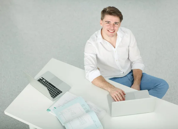 Schöner junger Mann sitzt und arbeitet am Laptop — Stockfoto