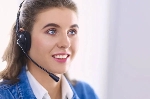 Feliz encantadora joven sentada y trabajando con el ordenador portátil con auriculares en la oficina — Foto de Stock