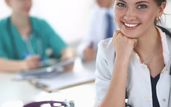 Hermosa joven sonriente doctora sentada en el escritorio — Foto de Stock