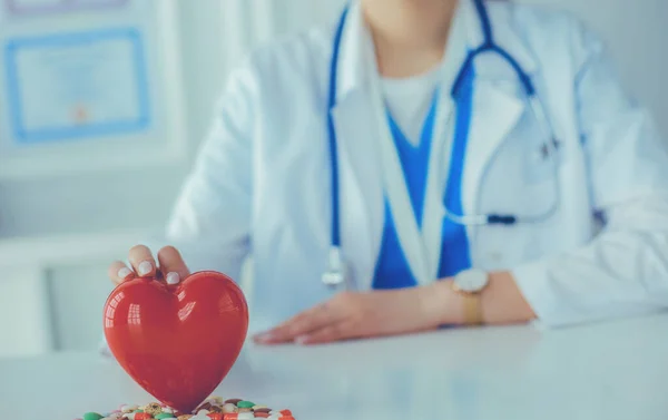 A doctor with stethoscope examining red heart, isolated on white background — Stock Photo, Image