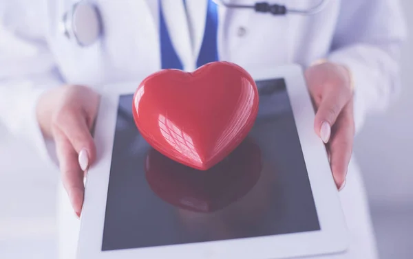 Médecin femme avec stéthoscope tenant le cœur, sur fond clair — Photo