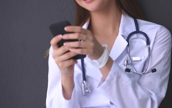 Genç bayan doktor yerde telefonunuzla oturuyor. — Stok fotoğraf