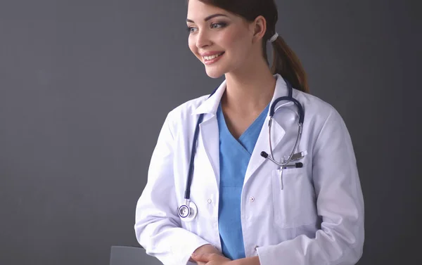 Médico fêmea bonita em pé perto de fezes isolado fundo cinza — Fotografia de Stock