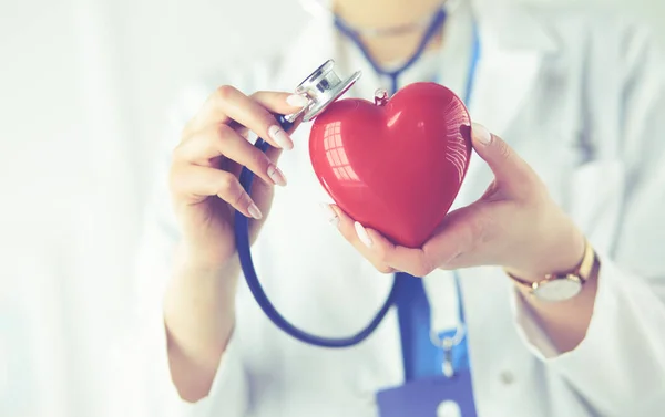 Egy sztetoszkópos orvos, aki vörös szívet vizsgál, fehér alapon elkülönítve. — Stock Fotó