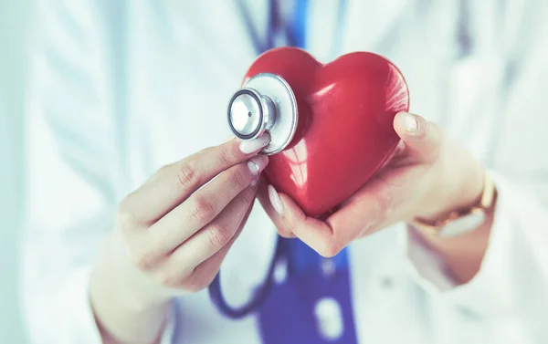 Ein Arzt mit Stethoskop untersucht rotes Herz, isoliert auf weißem Hintergrund — Stockfoto