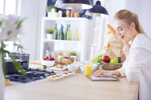 Hermosa joven usando una tableta digital en la cocina — Foto de Stock