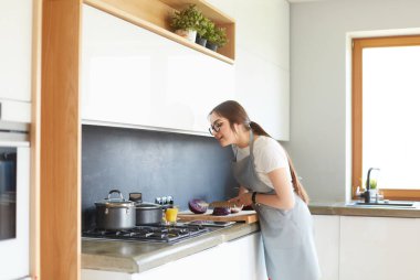 Mutfakta yemek yapmak için tablet bilgisayar kullanan genç bir kadın.