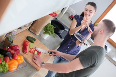 Bir çift evdeki mutfaklarında birlikte yemek pişiriyor.