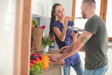 Bir çift evdeki mutfaklarında birlikte yemek pişiriyor.