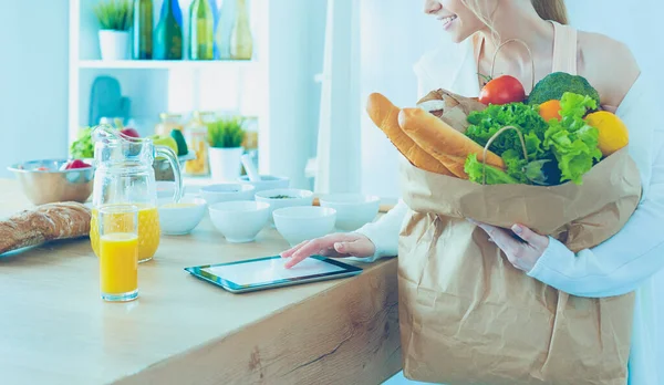 Young woman holding grocery shopping bag with vegetables .Standing in the kitchen — Stock Photo, Image