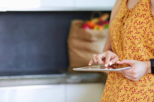 Hermosa joven usando una tableta digital en la cocina. — Foto de Stock