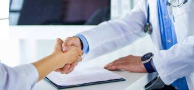 Doktor masadaki hastaya el sıkışıyor.