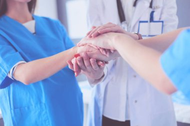 Doktorlar ve hemşireler tıbbi bir ekipte el ele tutuşuyorlar.
