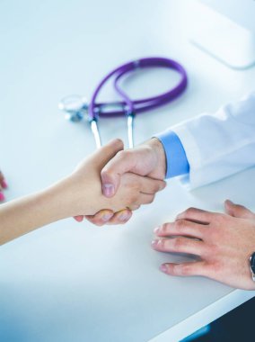 Doktor masadaki hastaya el sıkışıyor.