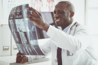 Genç Afrikalı doktor portresi hastaların röntgenlerini tutuyor.