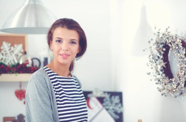 Genç bir kadın mutfakta duruyor.