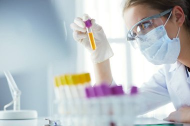 Modern laboratuvar veya hastanede plastik tıbbi tüplerle çalışan araştırmacı, doktor, bilim adamı veya laboratuvar asistanı