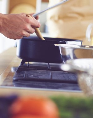 Dijital tablet ve yemek pişirme tarifine uyan bir adam evdeki mutfakta lezzetli ve sağlıklı yemekler pişiriyor.