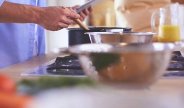 Dijital tablet ve yemek pişirme tarifine uyan bir adam evdeki mutfakta lezzetli ve sağlıklı yemekler pişiriyor.