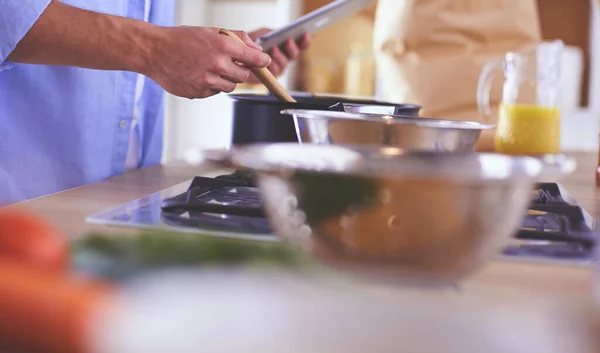 Man following recipe on digital tablet and cooking tasty and healthy food in kitchen at home