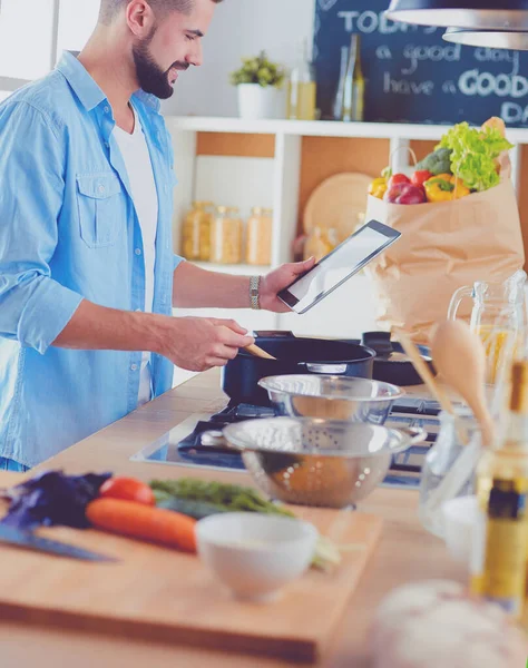 Mann folgt Rezept auf digitalem Tablet und kocht leckeres und gesundes Essen in der heimischen Küche — Stockfoto