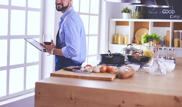 Hombre siguiendo la receta en la tableta digital y cocinar comida sabrosa y saludable en la cocina en casa —  Fotos de Stock