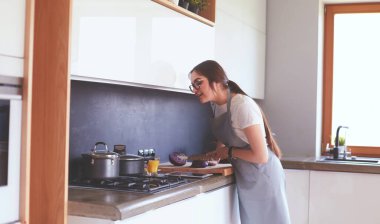 Mutfakta yemek yapmak için tablet bilgisayar kullanan genç bir kadın.
