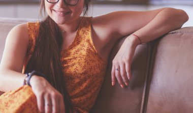 Kanepede oturan gülümseyen kadın portresi. Günlük tarz kapalı çekim.