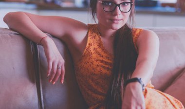 Kanepede oturan gülümseyen kadın portresi. Günlük tarz kapalı çekim.