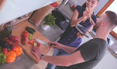 Bir çift evdeki mutfaklarında birlikte yemek pişiriyor.