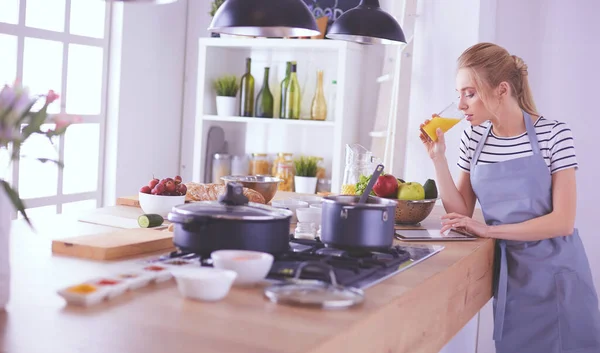 Atractiva mujer sosteniendo un vaso de jugo de naranja mientras está de pie en la cocina —  Fotos de Stock