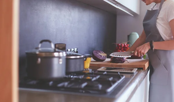 Молода жінка використовує планшетний комп'ютер для приготування їжі на кухні . — стокове фото