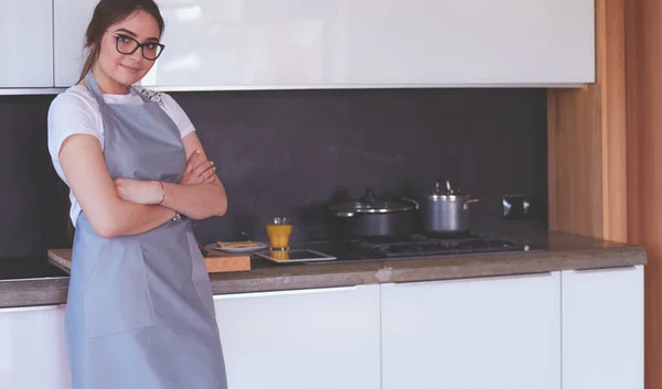 Retrato de jovem de pé com os braços cruzados contra o fundo da cozinha — Fotografia de Stock