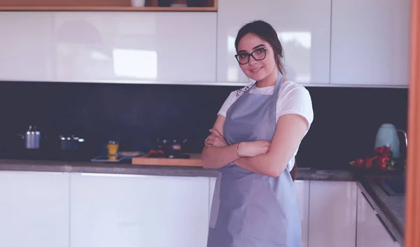 Kollarını mutfak arka planında kavuşturmuş genç bir kadının portresi. — Stok fotoğraf