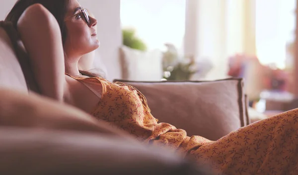 Relaxed woman sitting on a modern sofa at home — Stock Photo, Image