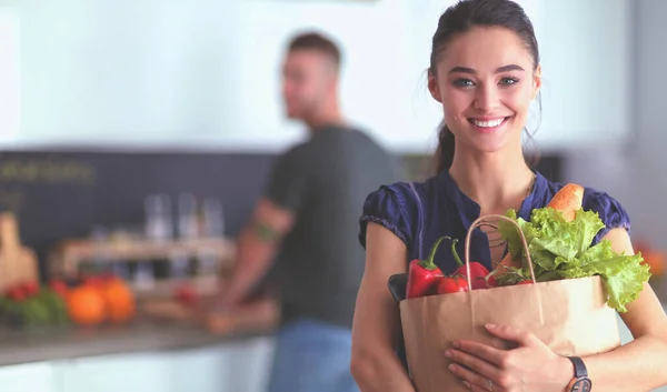 Unga par i köket, kvinna med en påse livsmedel shopping — Stockfoto