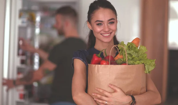 Young couple in the kitchen , woman with a bag of groceries shopping — Stock Photo, Image