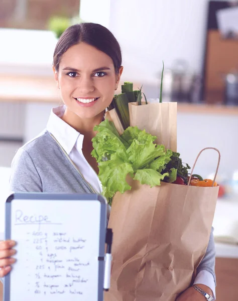 Jovem mulher segurando supermercado saco de compras com legumes .Standing na cozinha — Fotografia de Stock