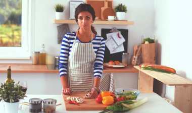 Mutfakta sebze doğrayan genç bir kadın.