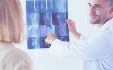 Yakışıklı doktor genç bayan hastasıyla konuşuyor ve ofisinde otururken notlar alıyor..