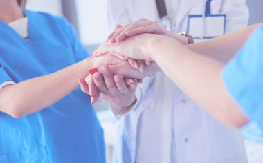 Doktorlar ve hemşireler tıbbi bir ekipte el ele tutuşuyorlar.