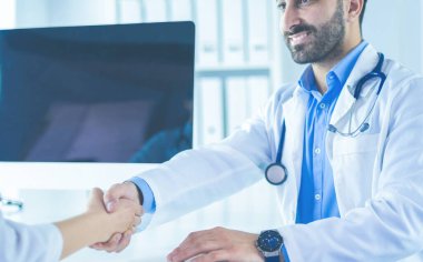 Doktor masadaki hastaya el sıkışıyor.