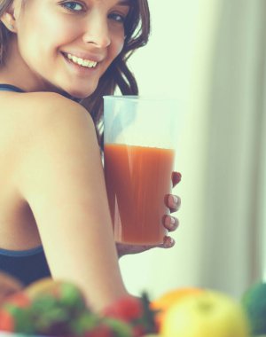 Mutfakta masada meyve suyu ve bardakla oturan bir kız.